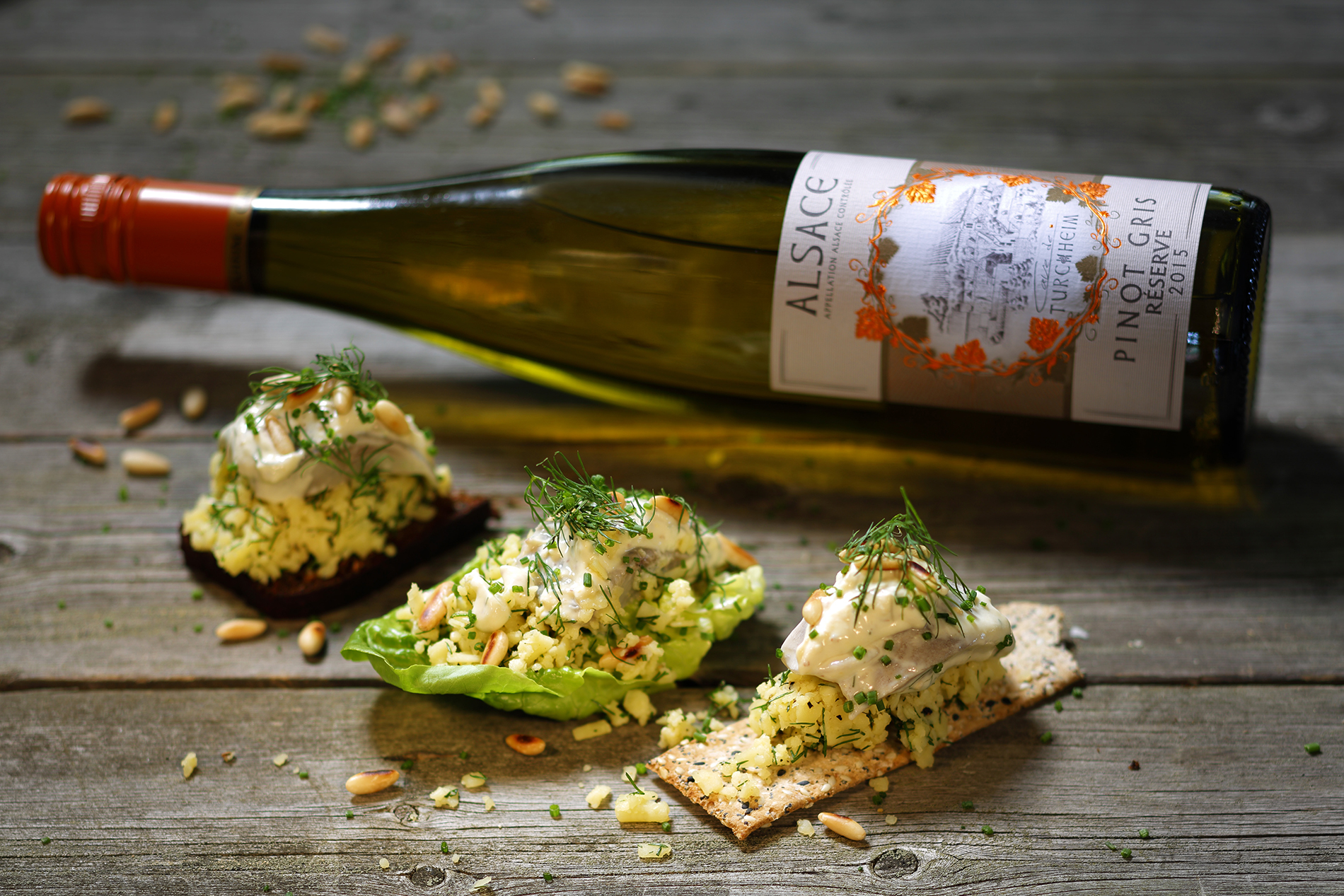 små snittar med sill och en vinflaska