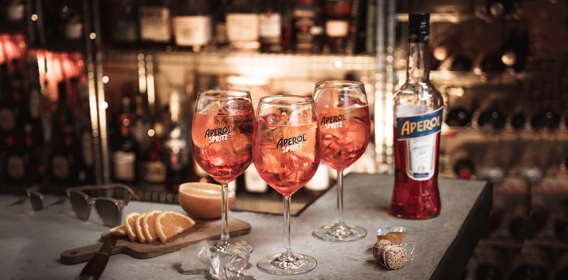 aperol spritz tre stycken med flaska på bord med apelsin
