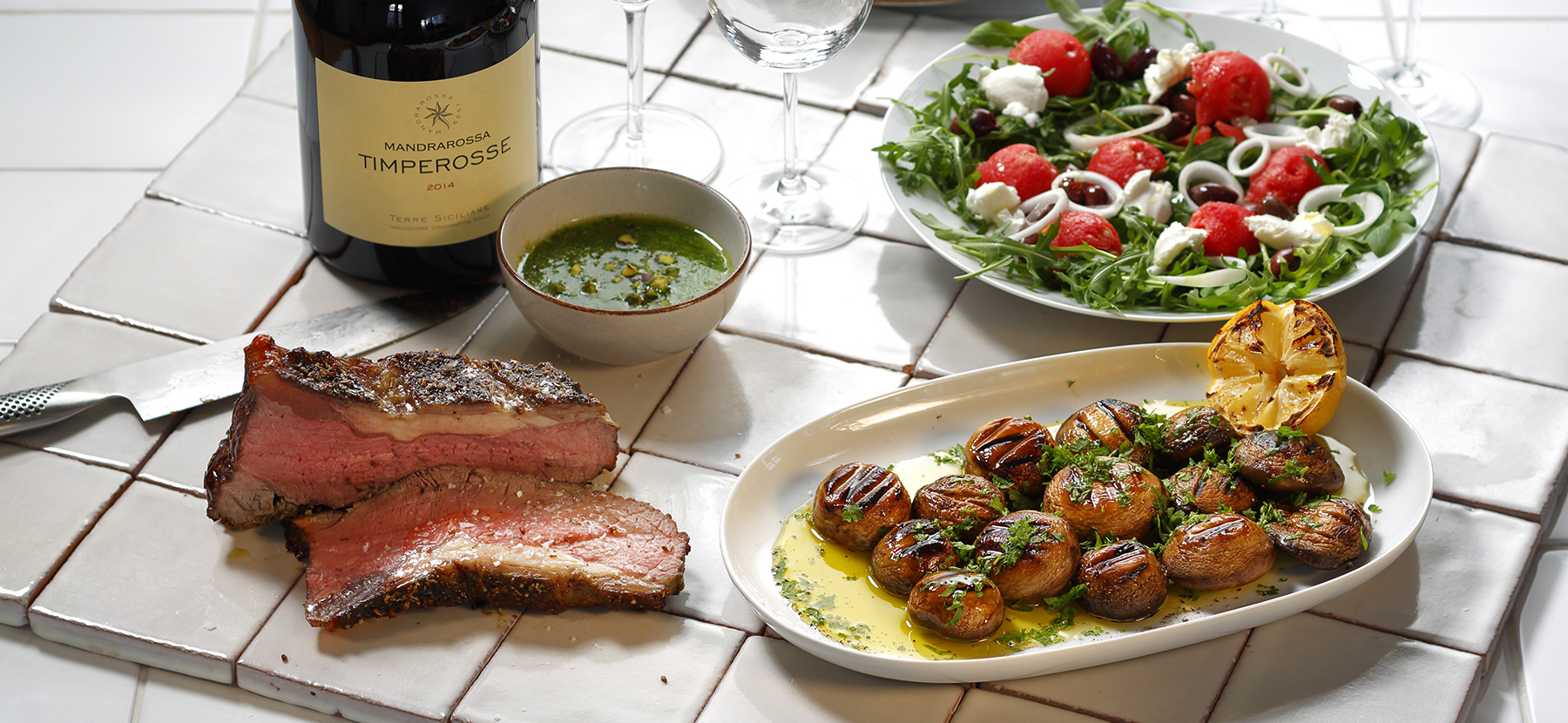 grillat kött med grönsaker och en flaska vin