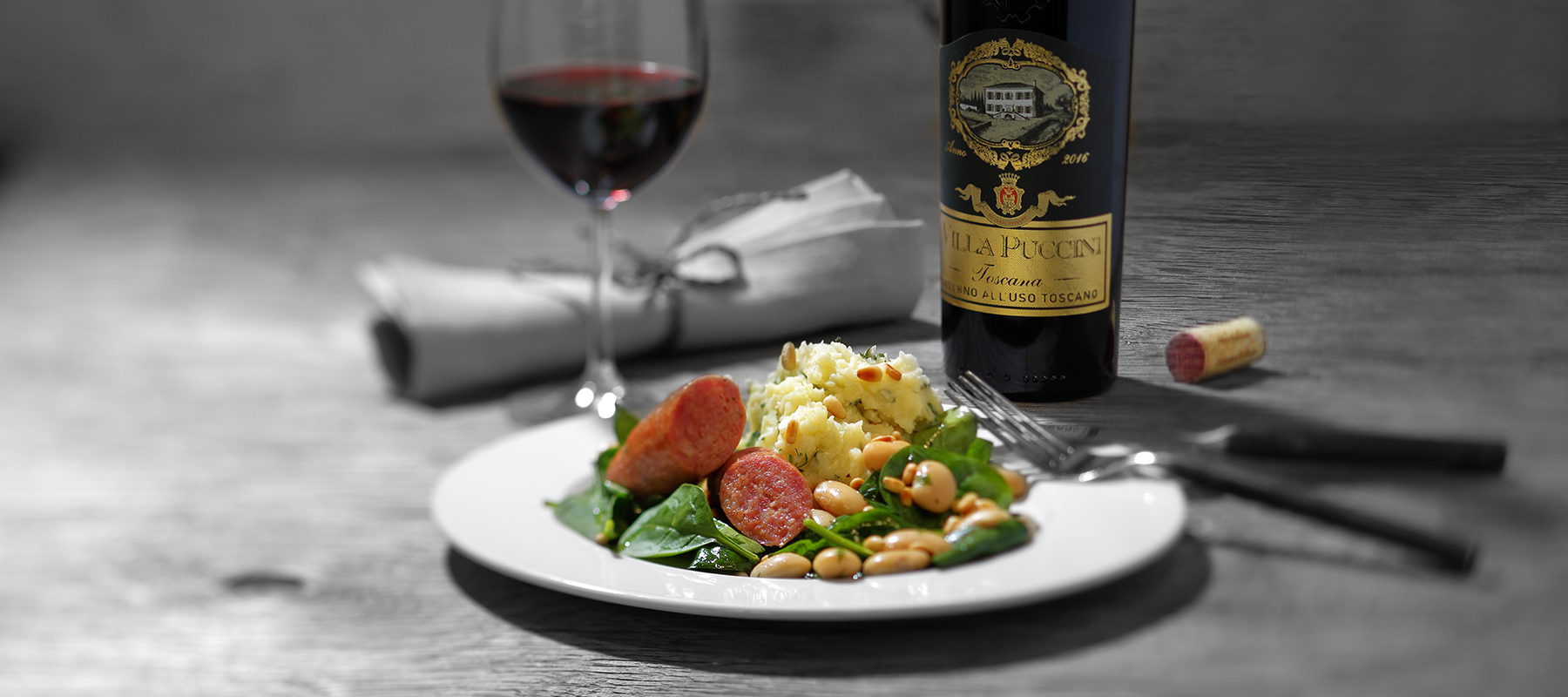 en tallrik med vita böner och korv med vinflaska