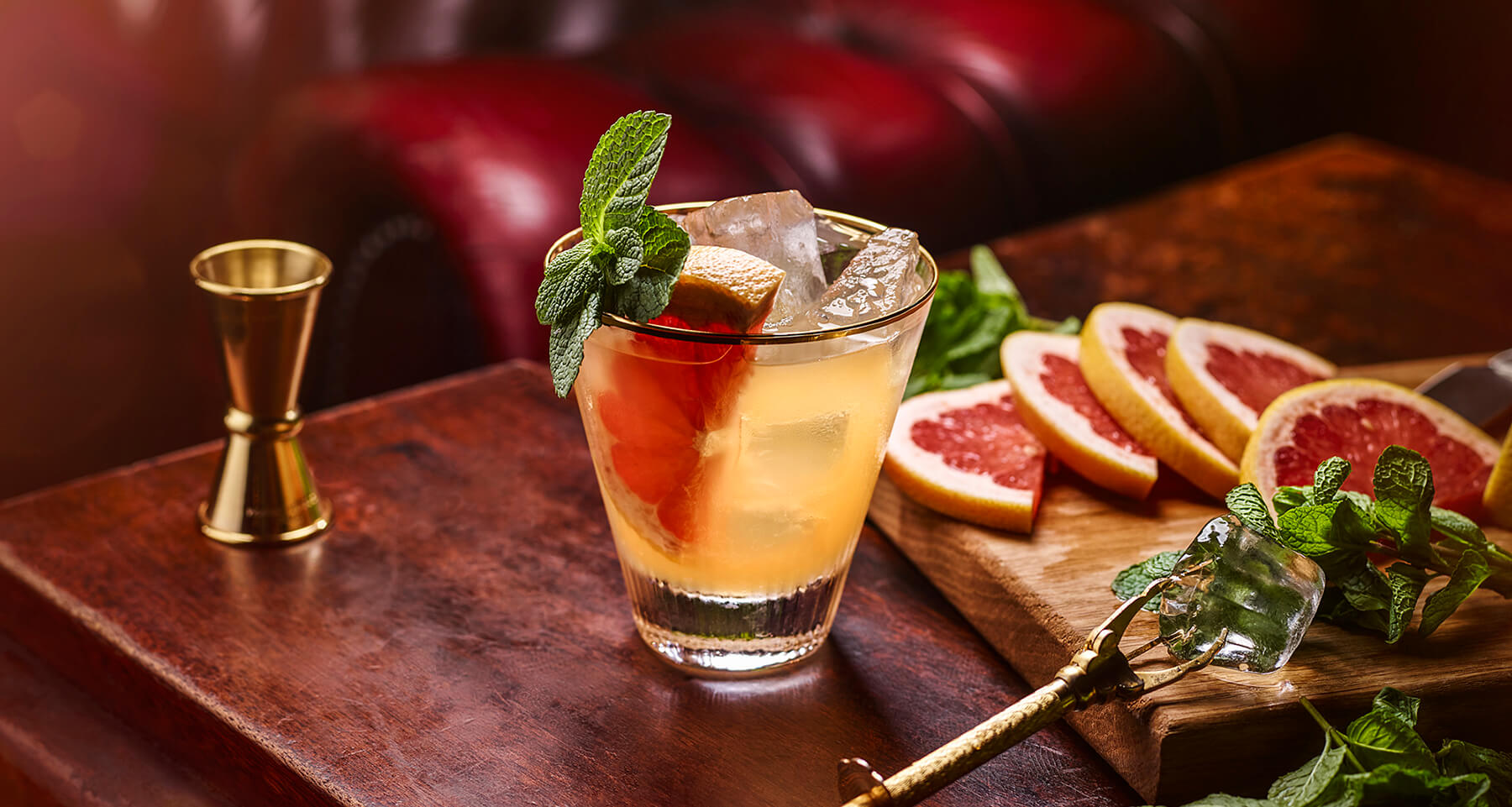 Ett glas fyllt av is, en skiva grapefrukt, en kvist mynta och cocktailen Fresco.