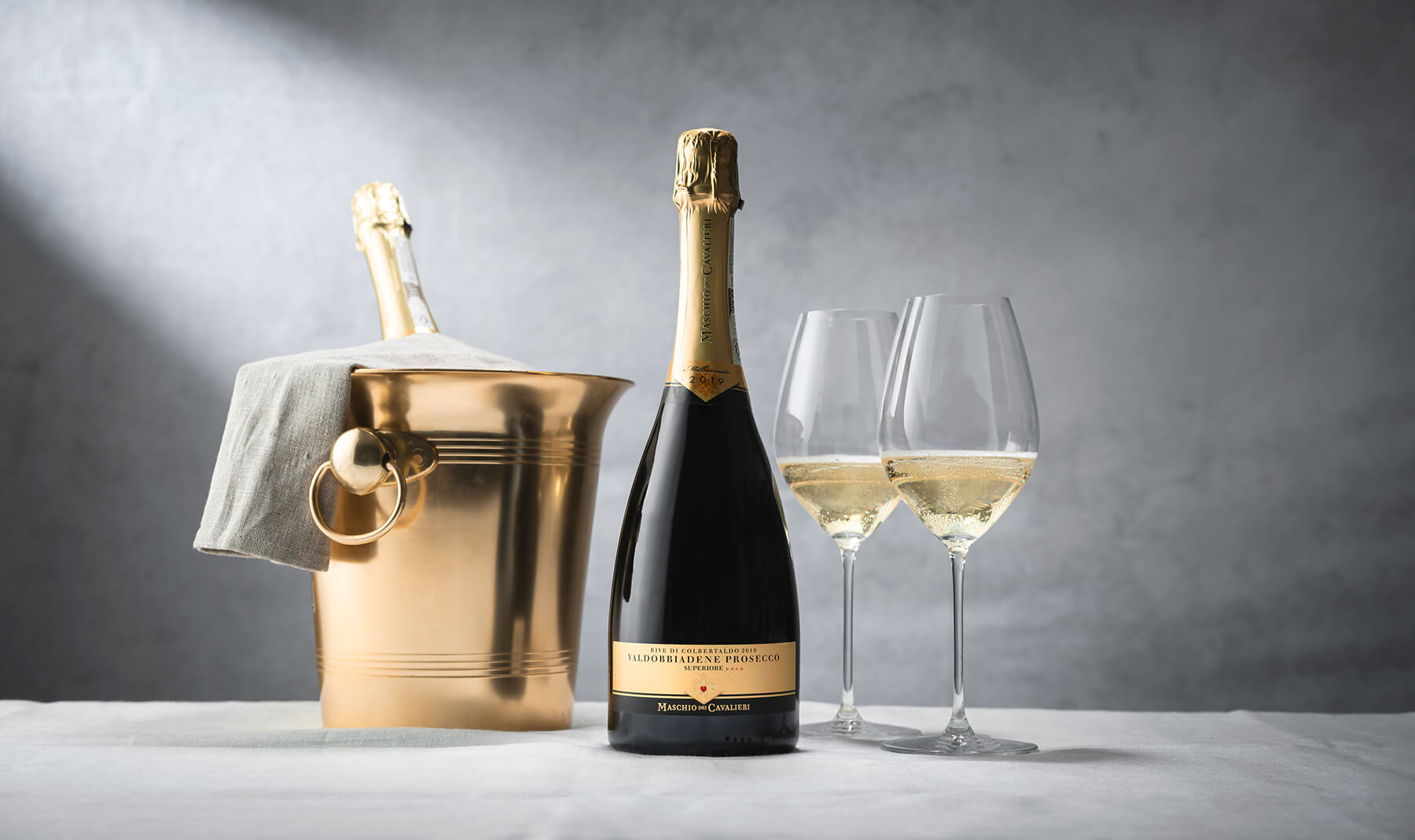 en flaska prosecco maschio och ishink med två glas mousserande