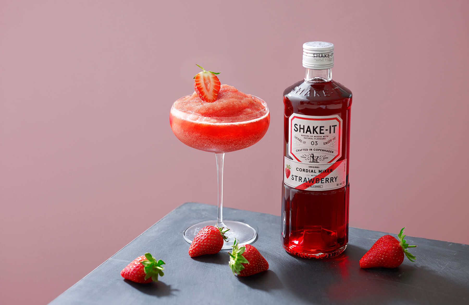 en flaska med jordgubbar på bord