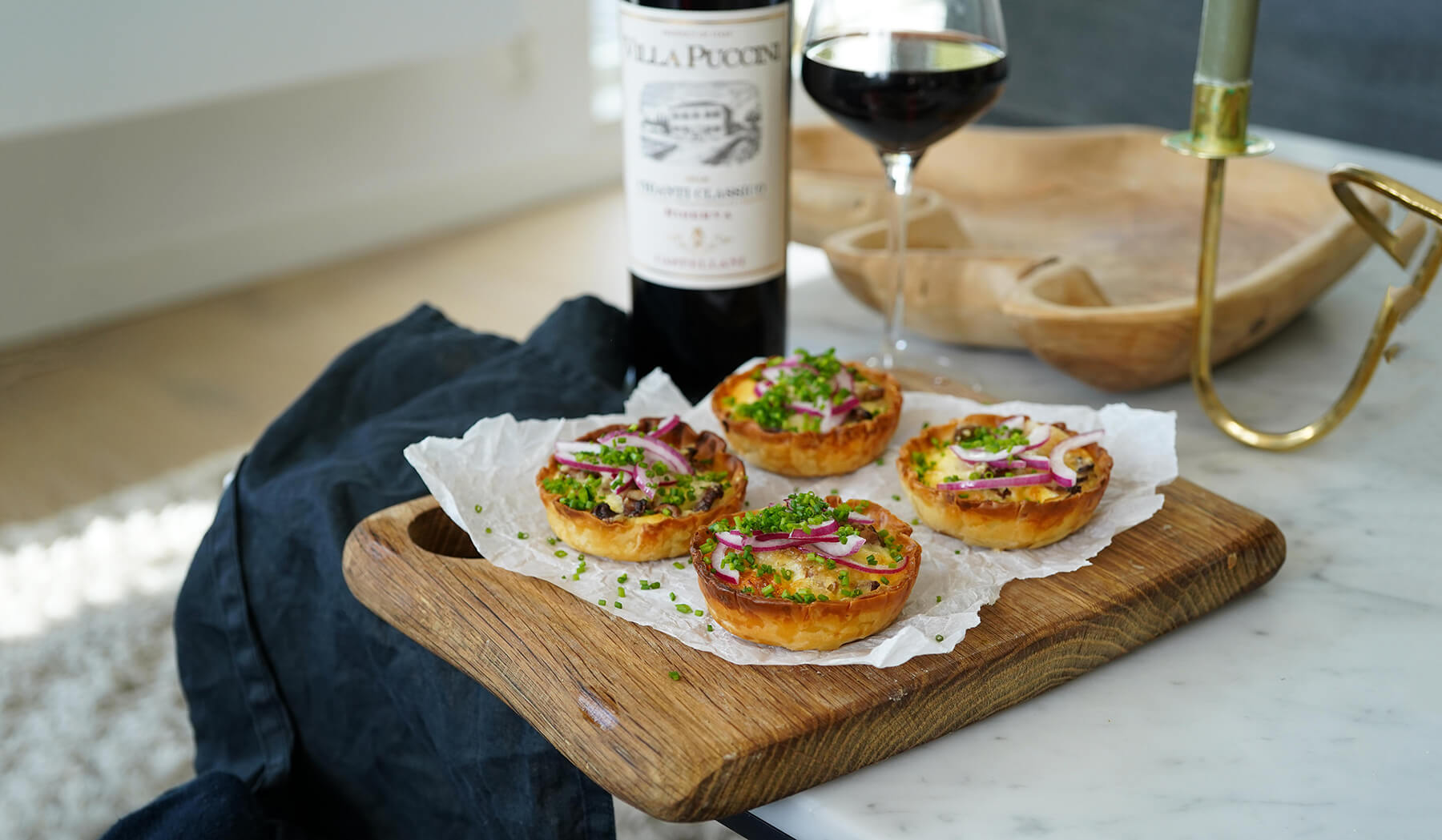 små kantarellpajer med västerbottenost på en skärbräda med en flaska vin