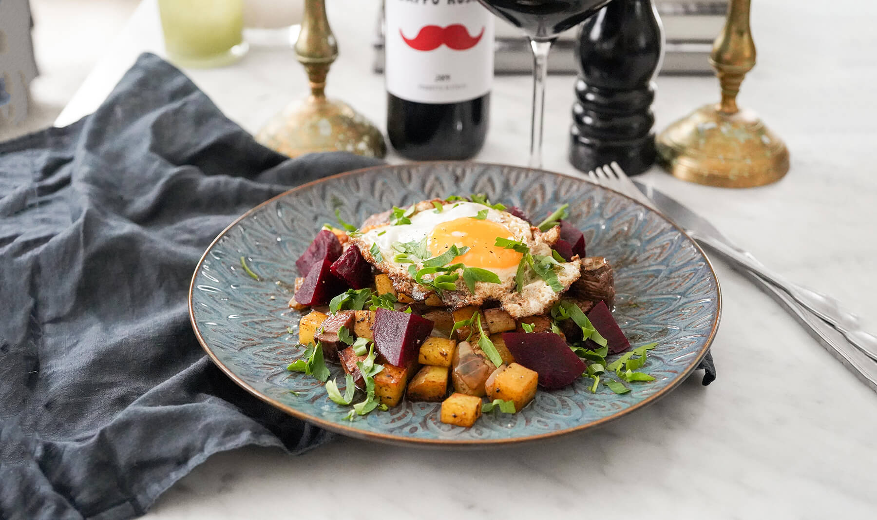 pytt i panna med stekt ägg på blå tallrik med pepparkvarn