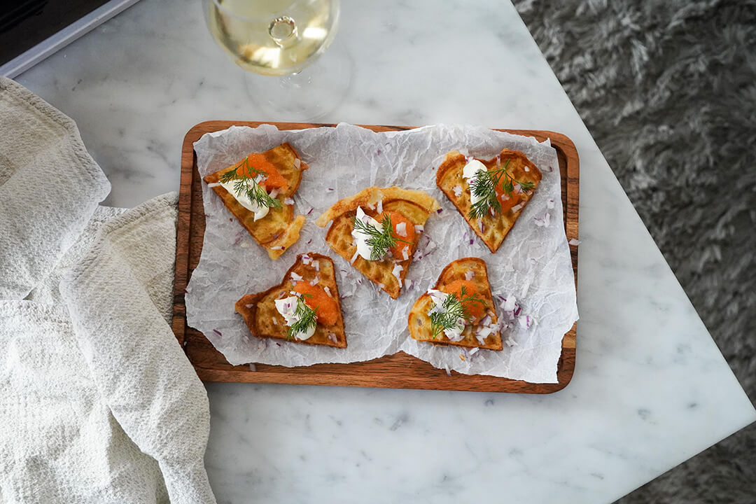 potatisfåffla på bord med ett glas bubbel och vitt vin