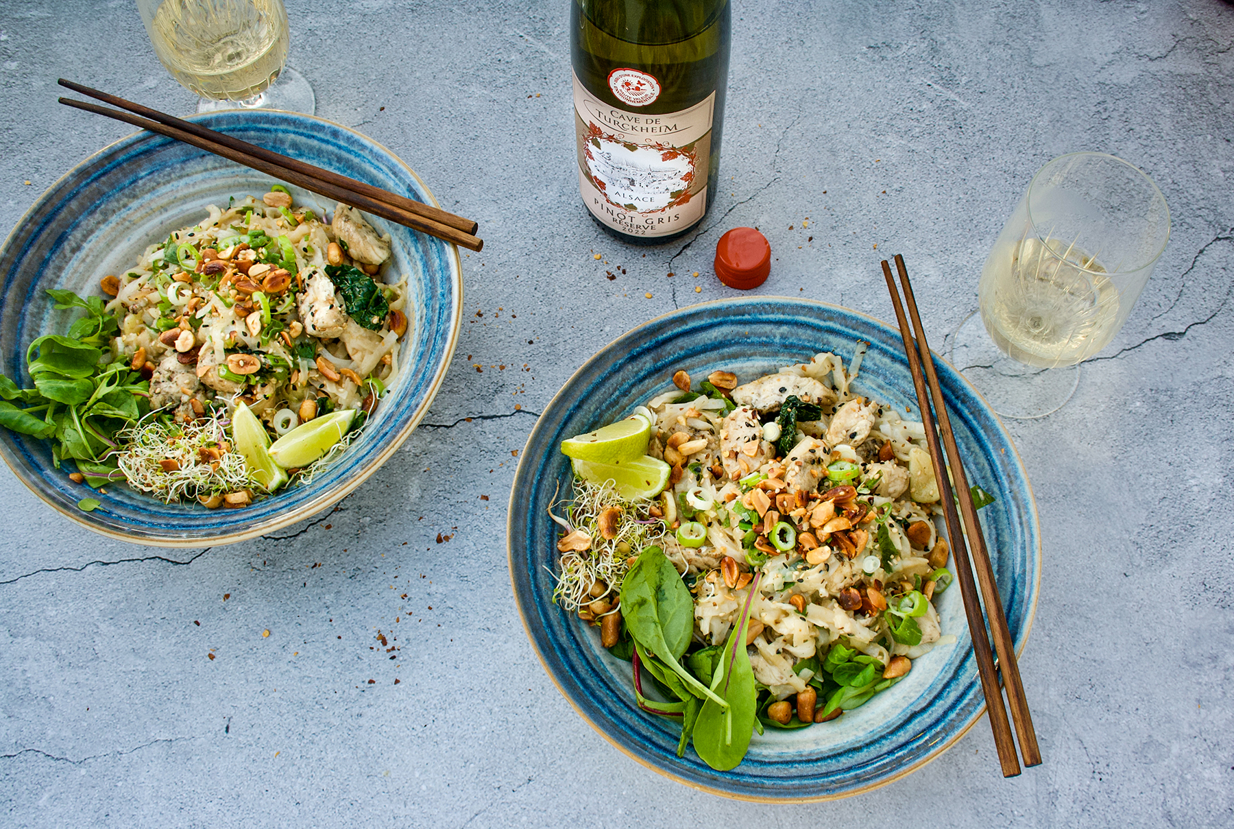 två tallrikar pad thai på lite olika sätt med vinflaska