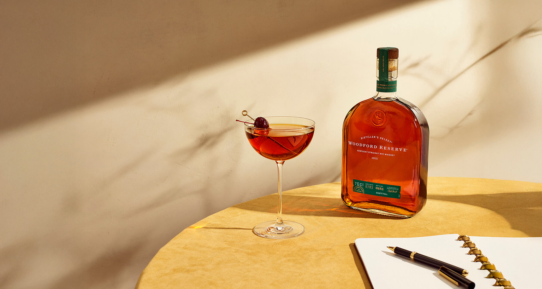 en flaska woodford whiskey på ett bord med block och penna